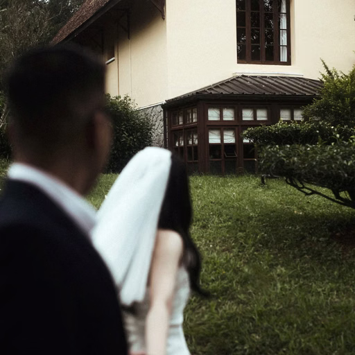 A groom looks at the bride through her veil in a garden.