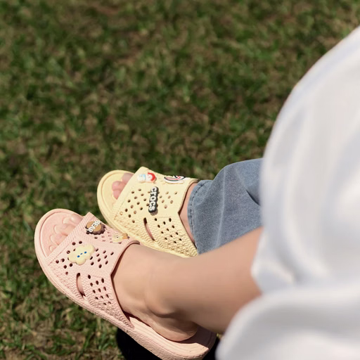Close-up of a couple's pink and yellow sandals on the grass at Cây Thông Cô Đơn, Đà Lạt