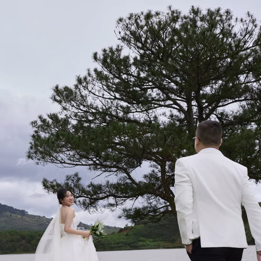 The bride walking towards the groom beneath the lakeside pine at Cây Thông Cô Đơn, Da Lat