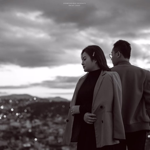 Black-and-white photograph of the couple with their backs to the camera, overlooking the city.