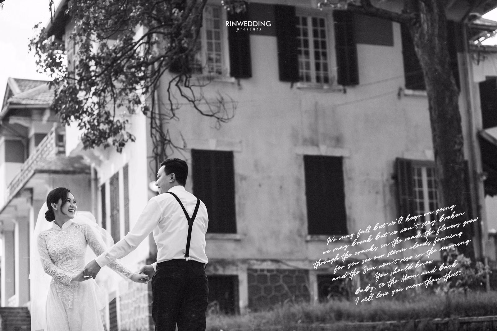 Black-and-white photograph of a bride and groom holding hands before a mansion.