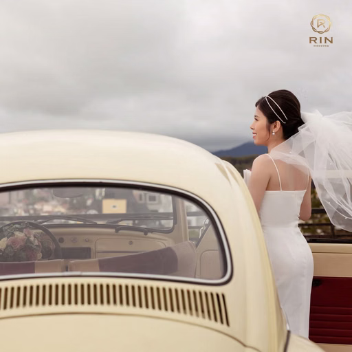 The couple on opposite sides of an ivory vintage car, looking at each other.