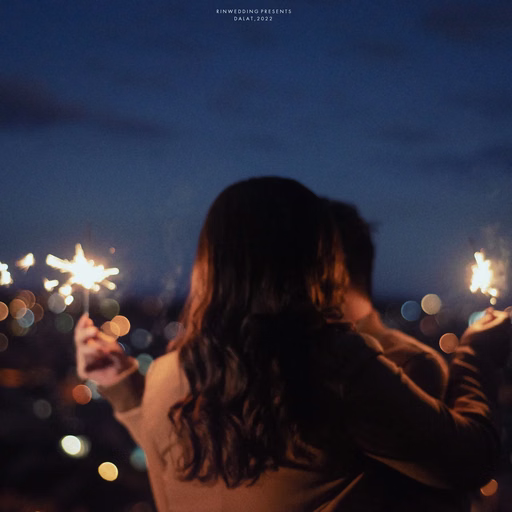 The bride seen from behind holding two sparklers before city lights.