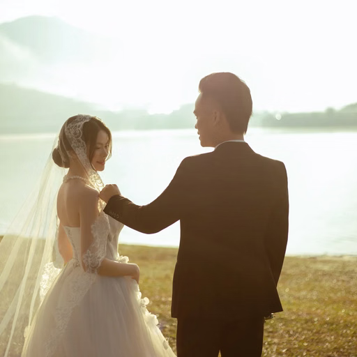The groom adjusts the bride's veil beside the lake at Cây Thông Cô Đơn, Đà Lạt