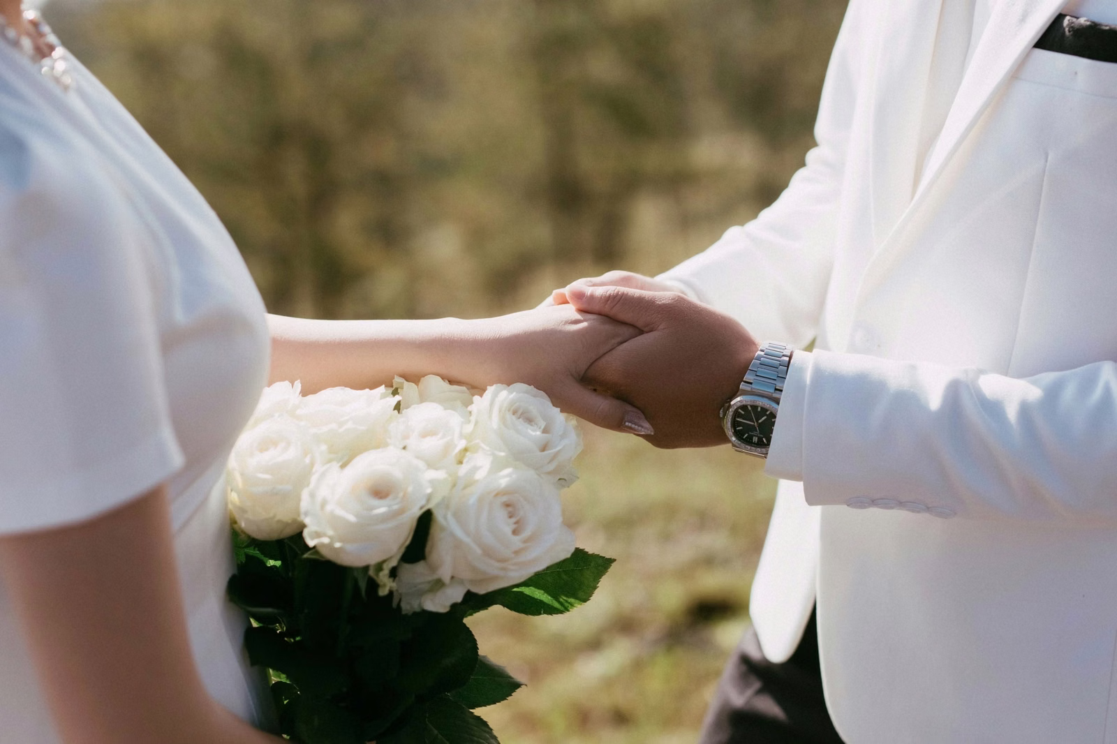 Close-up of the groom holding the bride's hand beside a white bouquet at Đồi Thông Đà Lạt