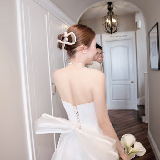 A bride looks back in a corridor, showing the large bow on the back of her dress, at The Nest, Đà Lạt