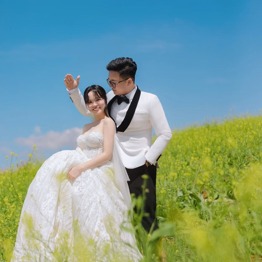 Cô dâu ngồi bên chú rể đang nâng tay giữa đồng hoa vàng tại Hoa Trong Rừng, Đà Lạt