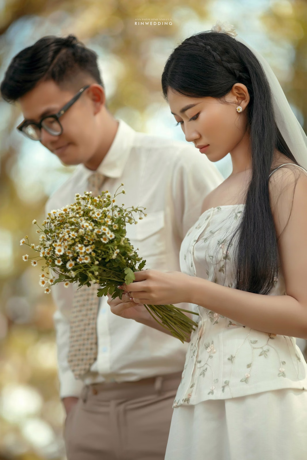 The bride and groom looking at a small bouquet in the garden of Dinh Tỉnh Trưởng.