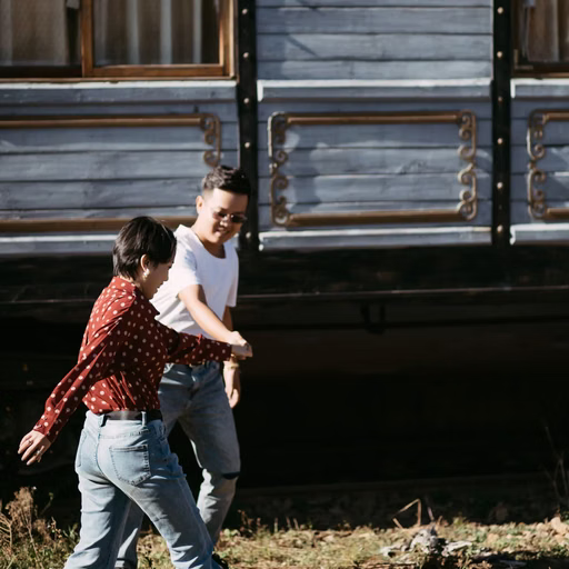 A couple playfully running beside a train carriage at Ga Đà Lạt.