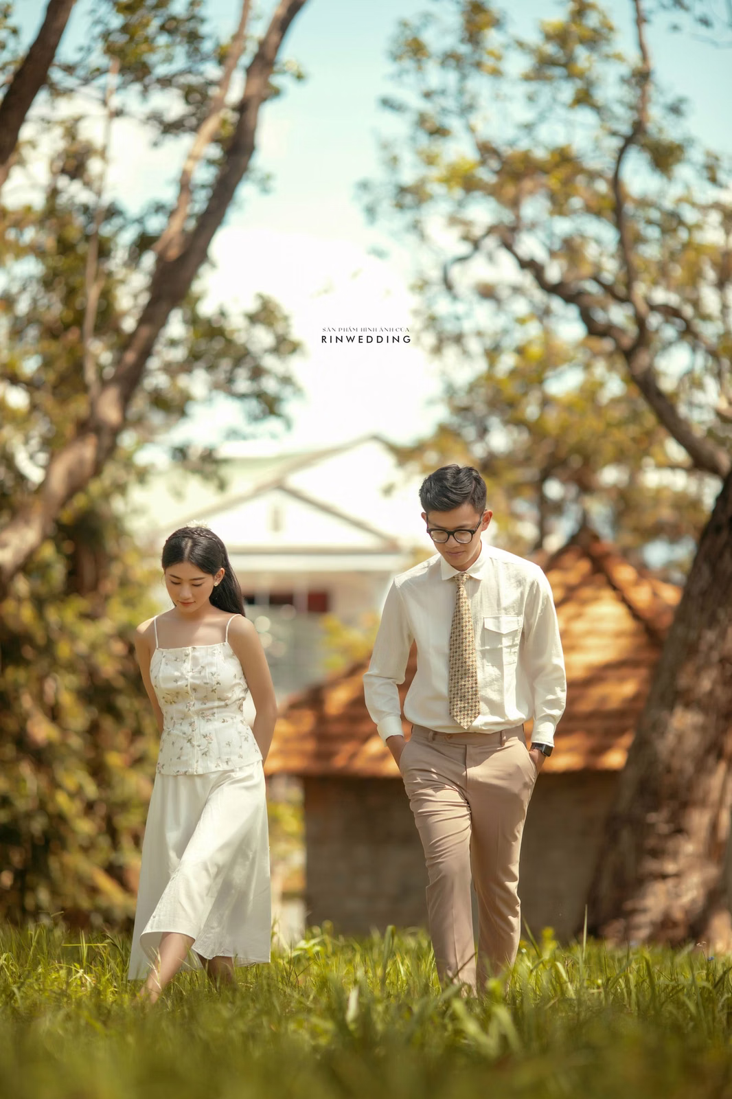 A bride and groom hold hands while crossing the lawn at Dinh Tỉnh Trưởng.