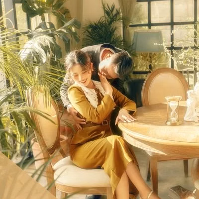 The man leans in to kiss the woman in a yellow dress beside a tea table at a Đà Lạt café.