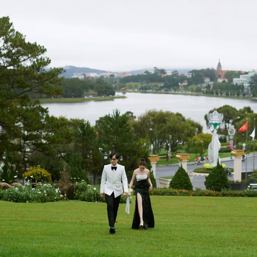 The bride and groom stand on the lawn overlooking hồ Xuân Hương.