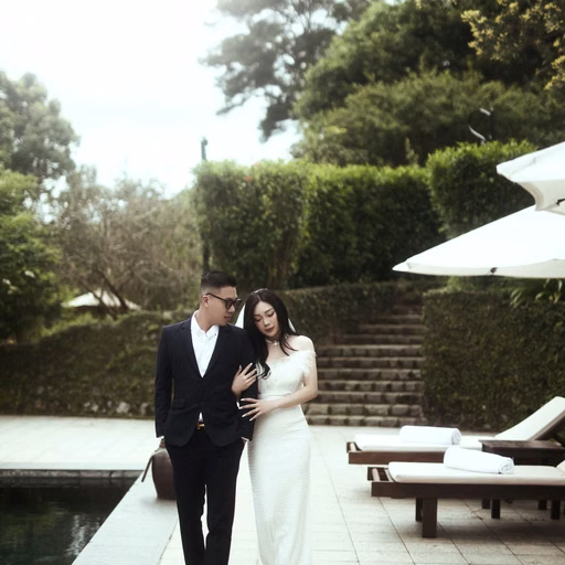 The bride and groom walk beside a resort pool.