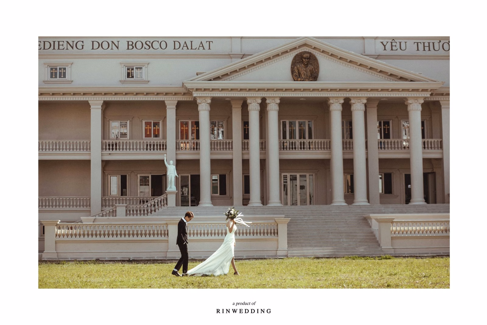 The bride and groom stand on the lawn before Nhà thờ Don Bosco