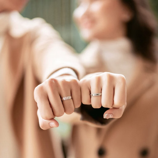 Close-up of the couple showing their wedding rings in brown-toned outfits.