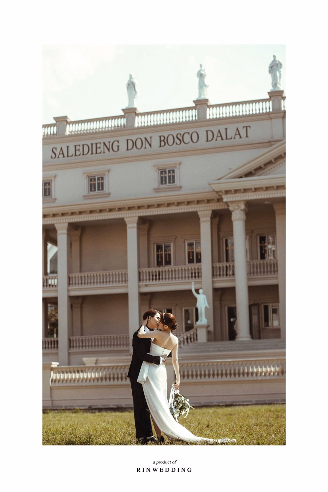 The bride and groom embrace before the colonnade at Nhà thờ Don Bosco