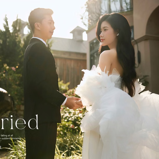 A bride looks back while holding the groom's hand in front of a building, with decorative text, at The Nest, Đà Lạt