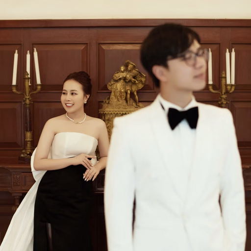 The groom standing in front of the bride in a wood-paneled room.