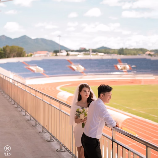 The groom carries the bride on his back along the stands at Sân Vận Động Đà Lạt.